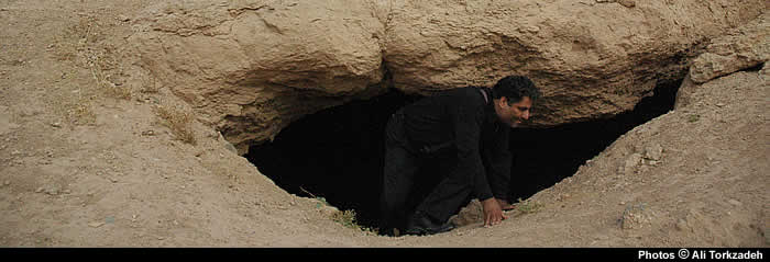 Archeologist Hassan Abdullahzadeh  stepping out of a 900-year-old wartime shelter, near Sabzevar, NE Iran.